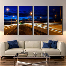 Load image into Gallery viewer, Moving car light trail through twilight city roads 4 piece canvas print In Living room
