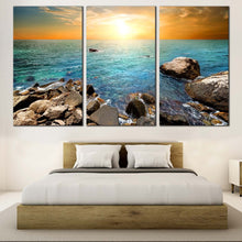 Load image into Gallery viewer, Stony Beach Canvas Wall Art Yellow Cloudy Sky Sunset  Triptych Canvas Print Blue Ocean Rocks Canvas In Bedroom
