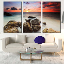 Load image into Gallery viewer, ocean boulders canvas wall art yellow red cloudy sky ocean canvas set brown ocean rocks beach 3 piece canvas print In Living Room
